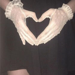 two hands in white lace gloves come together to form a heart.